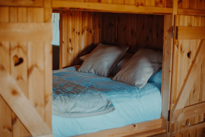 A cosy cabin bed with two pillows and a blue blanket, perfect for a good night's sleep for two.