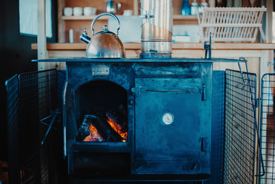 A cosy wood burning stove with a kettle on top, ready to cook a delicious meal. Perfect for a warm and tasty feast