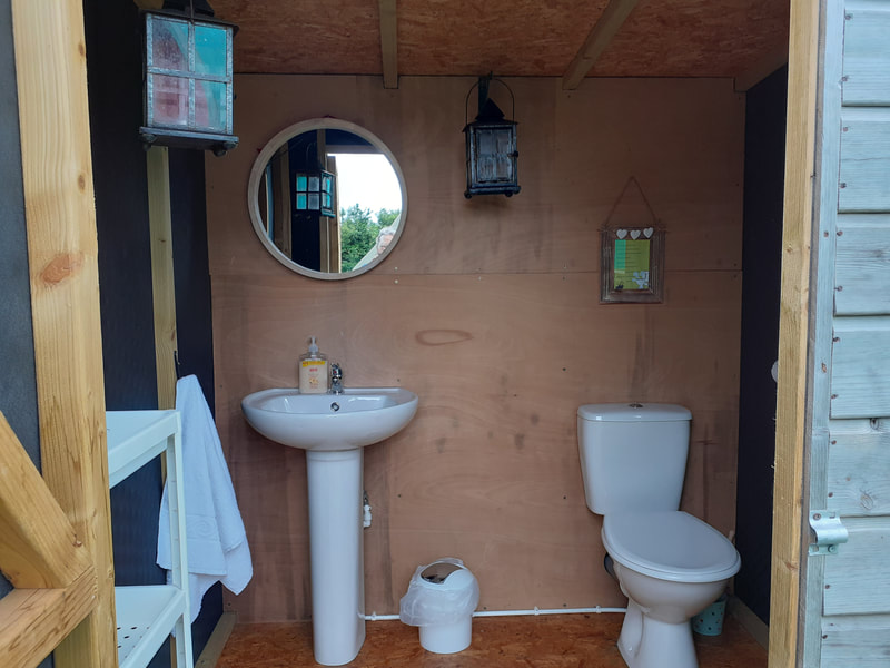 A cozy bathroom with a toilet, sink, and mirror. Enjoy your very own private toilet facilities!