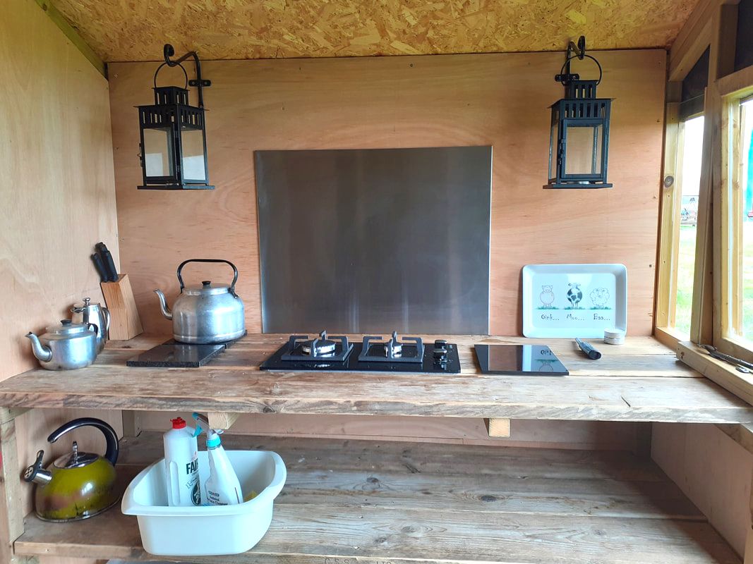 Inside our cooking shed, a well-equipped kitchen with a gas hob and a shelf.